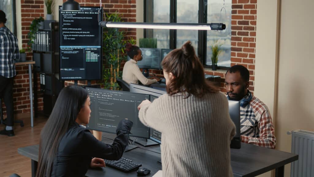 Software programer pointing pencil at source code on computer screen explaining algorithm to coworker - Software Development by Mantrax