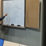 Technical lead and project manager leading a software architecture design session at a whiteboard