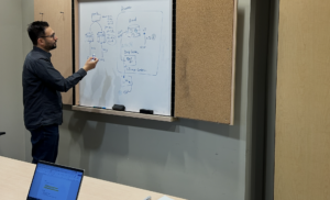 Technical lead and project manager leading a software architecture design session at a whiteboard